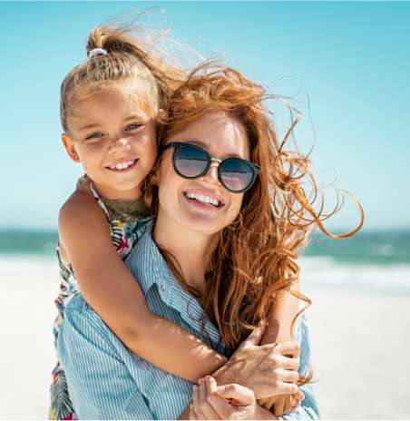 Rudowłosa kobieta z córką na wakacjach na białej plaży.